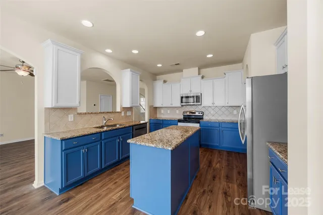 a large kitchen with stainless steel appliances granite countertop wooden cabinets a stove a sink and a refrigerator