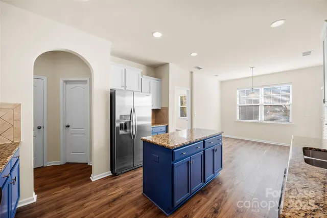 a kitchen with stainless steel appliances granite countertop a refrigerator a sink and wooden cabinets