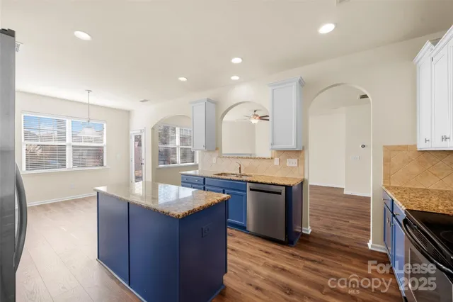 a large kitchen with granite countertop a sink counter space and stainless steel appliances