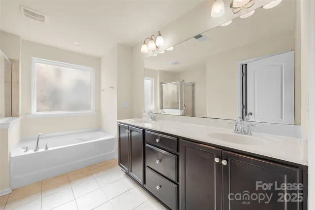 a spacious bathroom with a tub sink and mirror