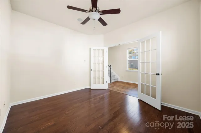a view of an empty room with a window and wooden floor