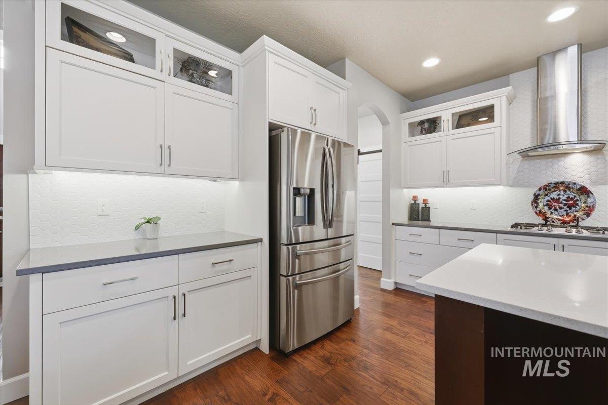1303 West Brando Street Meridian, ID 83646 - Photo 16 of 49 Open-concept kitchen featuring white shaker cabinetry, stainless steel appliances, dark wood-finish flooring, recessed lighting, and a white tile backsplash