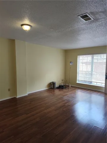 an empty room with wooden floor and windows with curtains