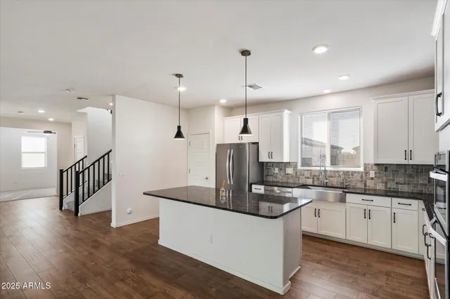 a kitchen with stainless steel appliances granite countertop a sink a stove a refrigerator and island with wooden floor