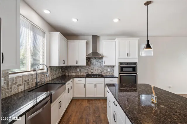 a kitchen with stainless steel appliances granite countertop a sink a stove and cabinets