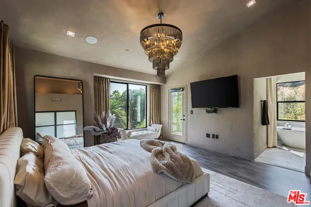 a bed room with a bed a television and a large window