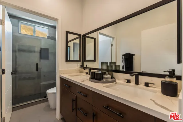 a bathroom with a double vanity sink mirror and shower