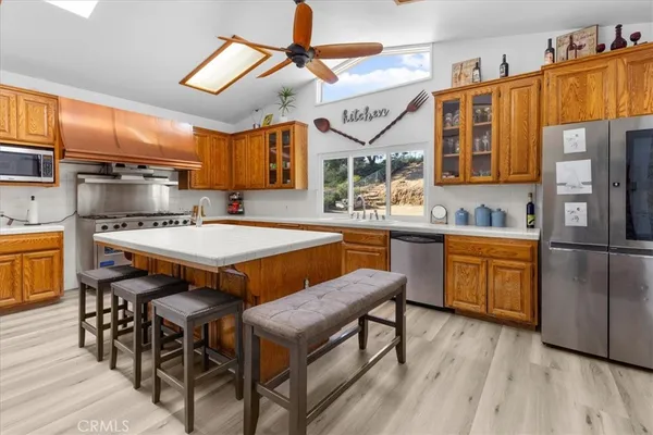 a dining hall with stainless steel appliances granite countertop a sink a stove and chairs with wooden floor