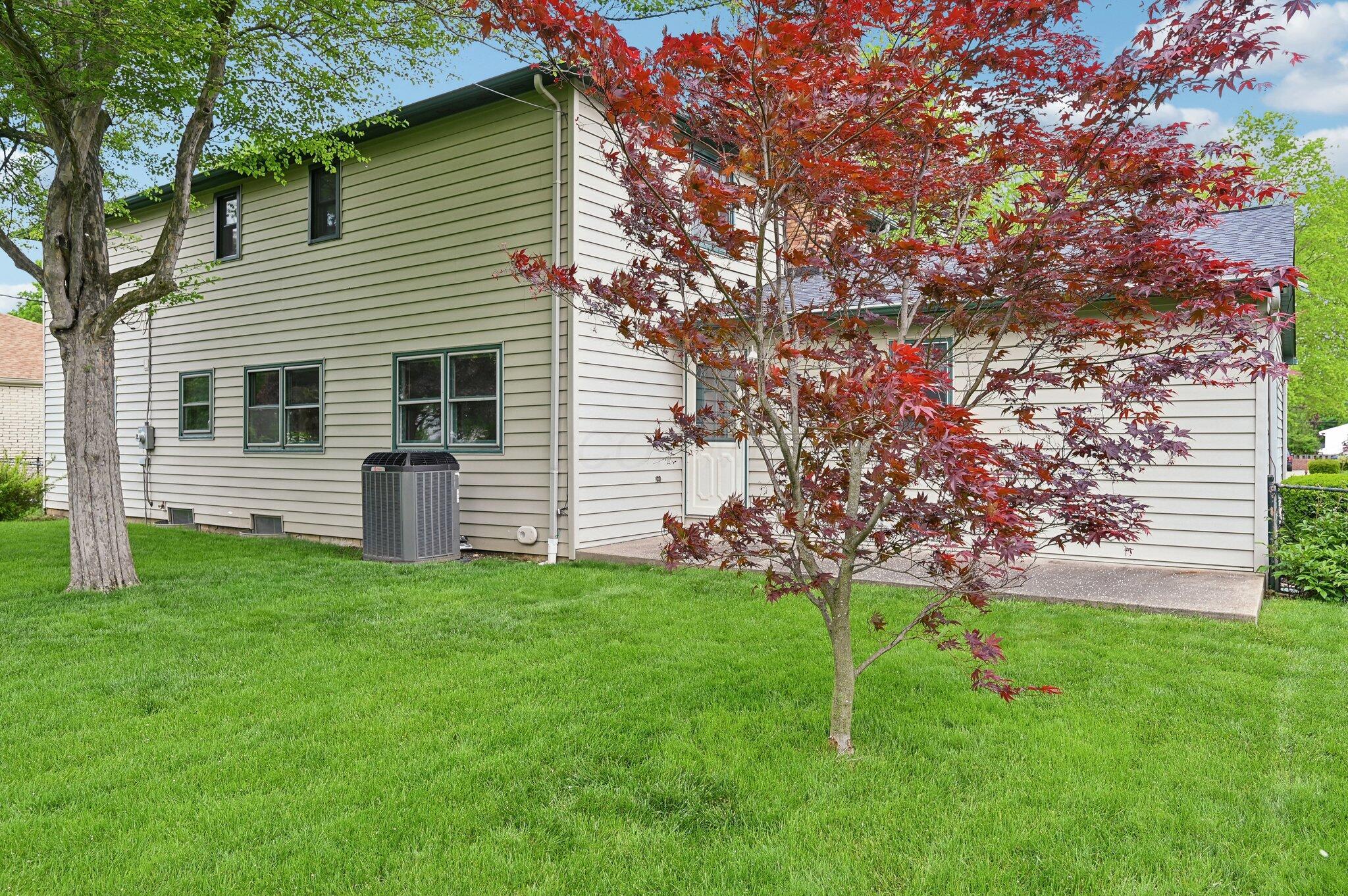 5917 Rocky Rill Road Columbus, OH 43235 - Photo 40 of 47 Rear Exterior
The home’s rear view highlights the updated HVAC unit, low-maintenance vinyl siding, concrete patio, and mature landscaping, including a vivid Japanese maple tree.