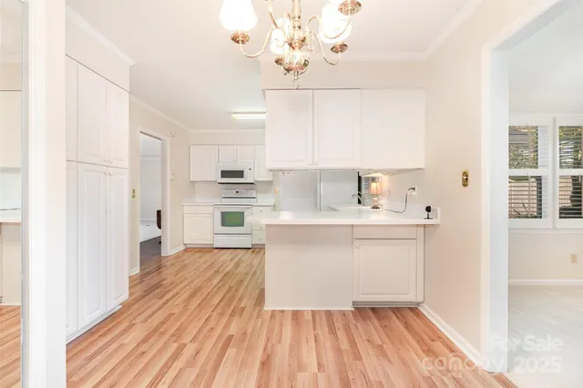 a view of empty room with wooden floor and chandelier