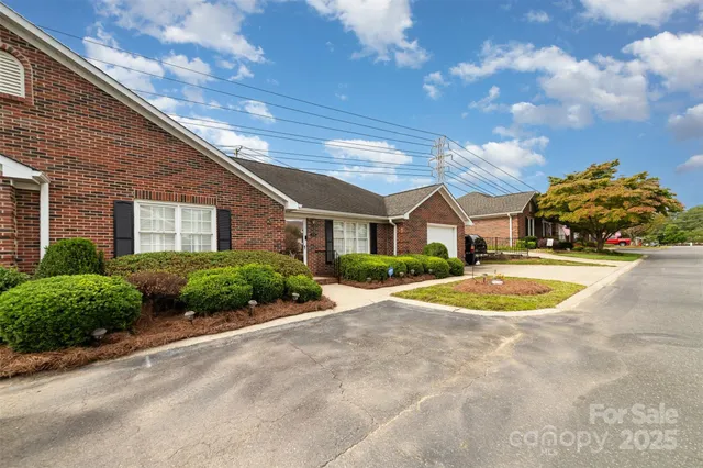 a view of a white house with a yard and table and chairs under an umbrella