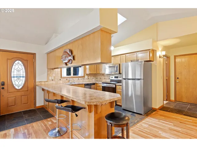 a kitchen with stainless steel appliances granite countertop a refrigerator a stove and a wooden floors