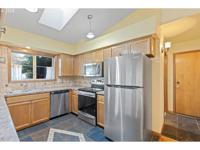 a kitchen with stainless steel appliances granite countertop a refrigerator a sink a stove and island