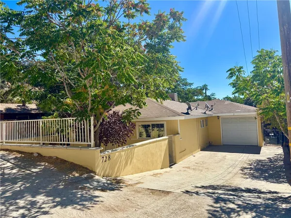 a view of a house with a large tree and wooden fence