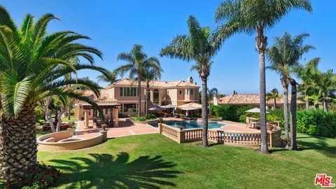 a view of a building with a yard and palm trees