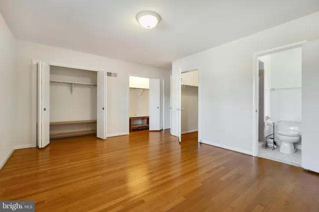 an empty room with wooden floor and bathroom view
