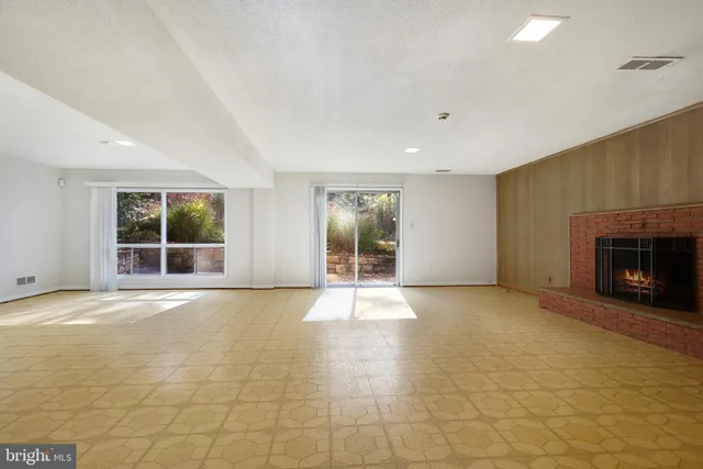 a view of an empty room with a window and fireplace