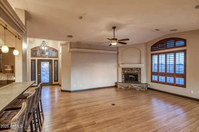 a view of an empty room with window and chandelier fan