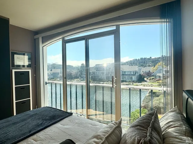 a bedroom with a bed and a large window with balcony view