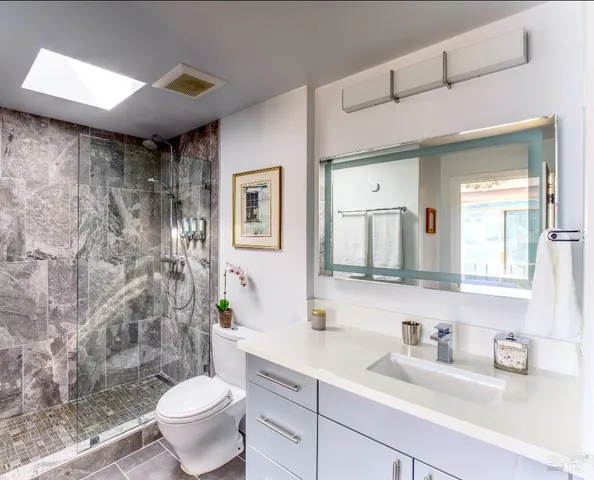 a bathroom with a granite countertop sink a toilet and shower