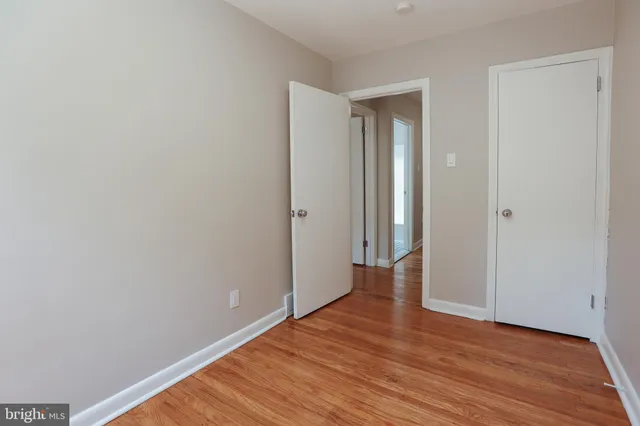 a view of an empty room with wooden floor and closet