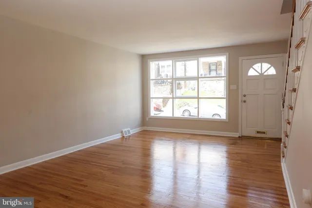 a view of an empty room with wooden floor and a window
