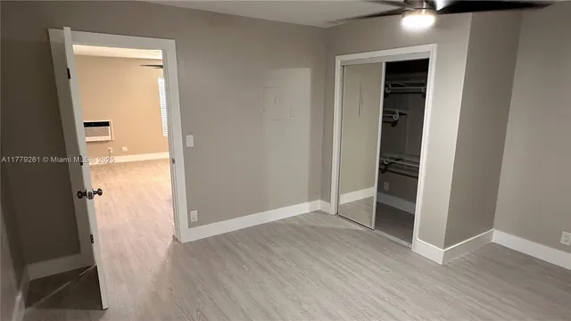 an empty room with wooden floor cabinet and door