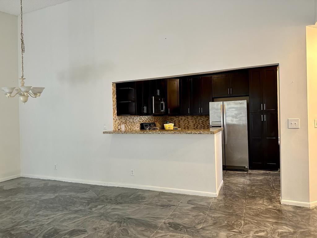 5438 Verona Drive, Unit 812 Boynton Beach, FL 33437 - Photo 11 of 35 a view of a refrigerator in kitchen and an empty room