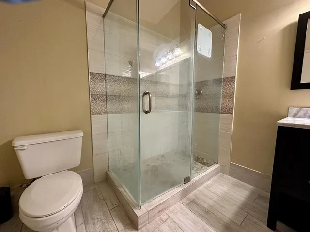 a bathroom with a granite countertop toilet a sink a shower and mirror