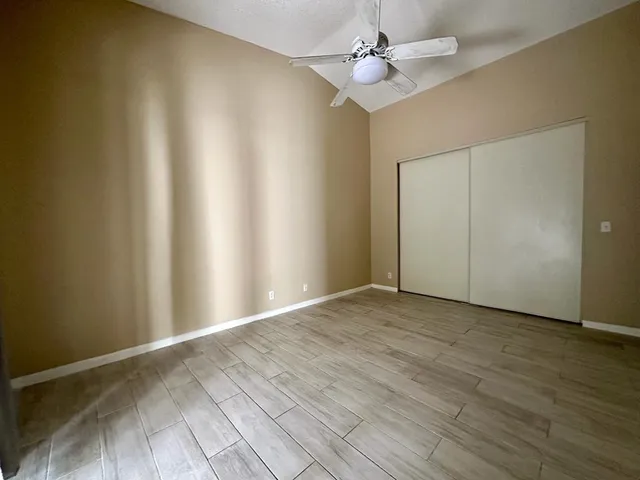 an empty room with wooden floor fan and windows