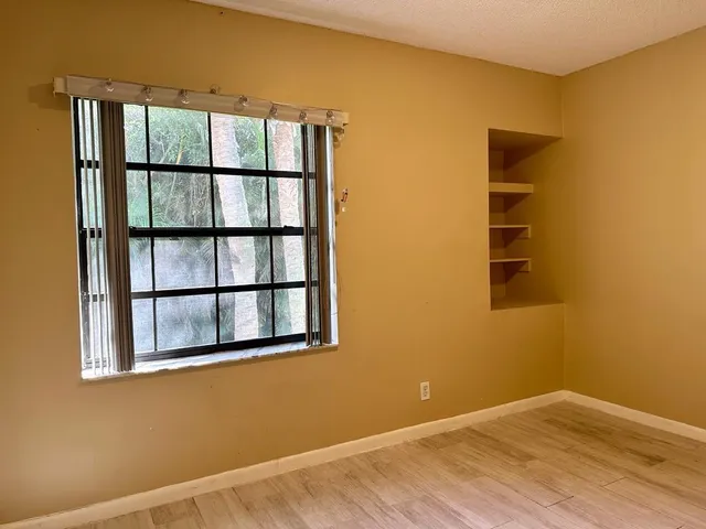 a view of an empty room with a window and wooden floor