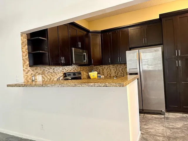 a kitchen with granite countertop a refrigerator and a stove