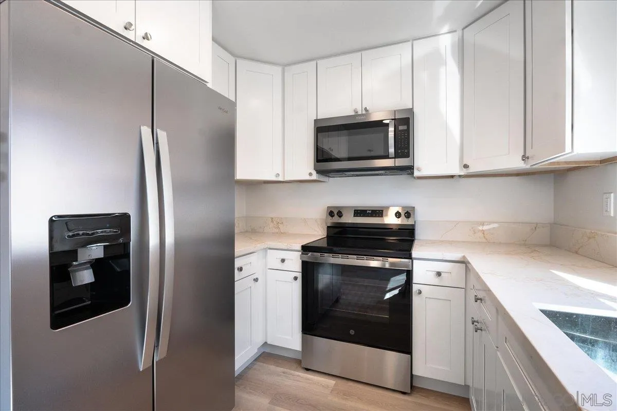 955 Postal Way, Unit 29 Vista, CA 92083 - Photo 3 of 32 a kitchen with stainless steel appliances granite countertop white cabinets a refrigerator and a stove top oven