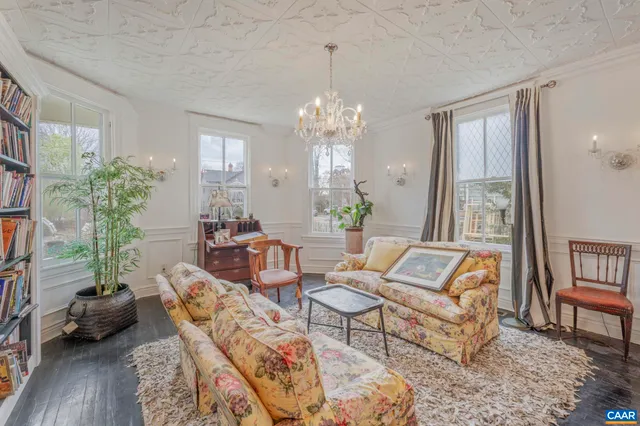 a living room with furniture a bookshelf and a chandelier