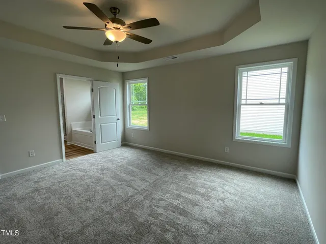 an empty room with chandelier fan and windows
