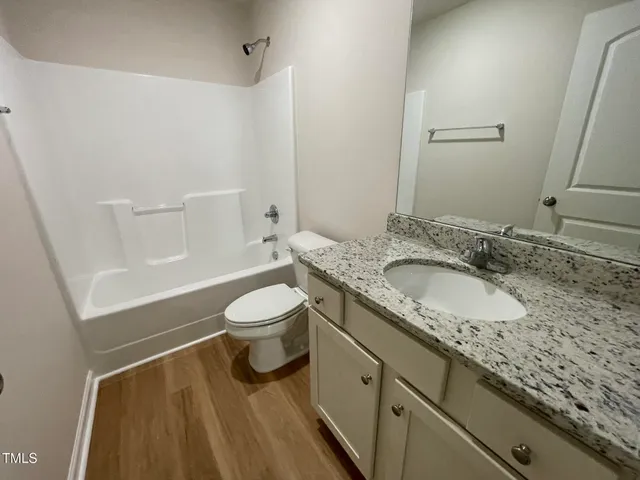 a bathroom with a granite countertop sink a toilet and shower