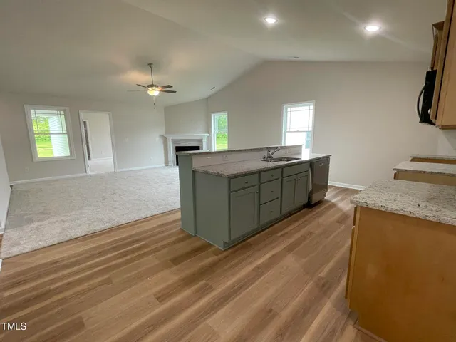 a large kitchen with kitchen island a stove a sink dishwasher and a refrigerator with wooden floor