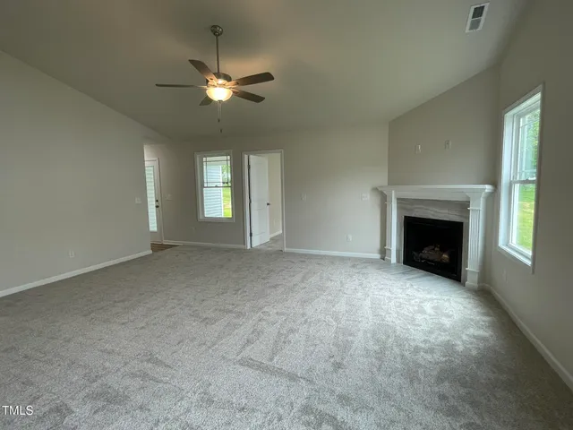 a view of an empty room with window and fireplace