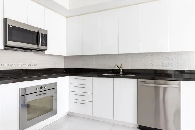 a kitchen with granite countertop white cabinets stainless steel appliances and sink