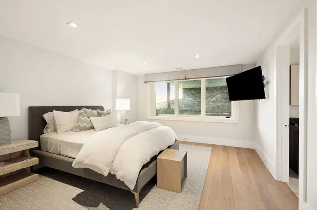 a bedroom with a bed and a flat tv screen next to a window