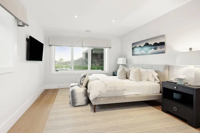 a bedroom with a large bed and a flat tv screen on a dresser