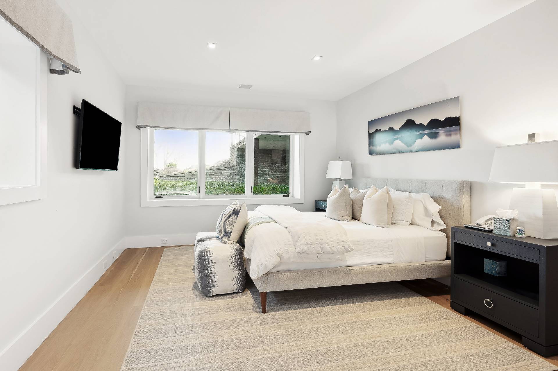 26 Mashomuck Drive Sag Harbor, NY 11963 - Photo 20 of 25 a bedroom with a large bed and a flat tv screen on a dresser