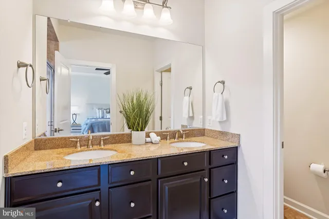 a bathroom with a granite countertop double vanity sink and mirror