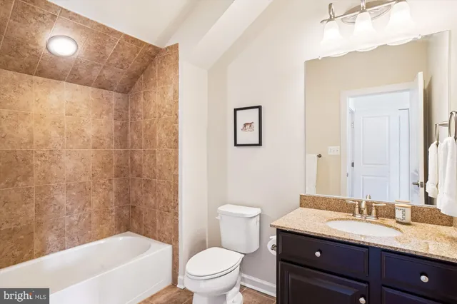 a bathroom with a granite countertop sink a toilet a mirror a bathtub and shower