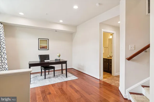 a view of a workspace room with wooden floor and furniture
