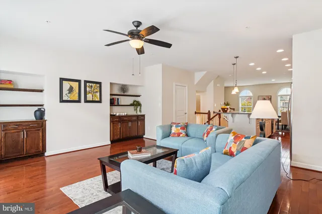 a living room with furniture kitchen view and a wooden floor