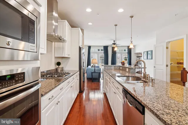 a kitchen with stainless steel appliances granite countertop a sink a stove and a wooden floors