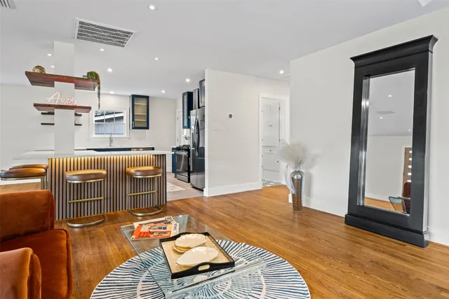 a living room with furniture a large window and wooden floor