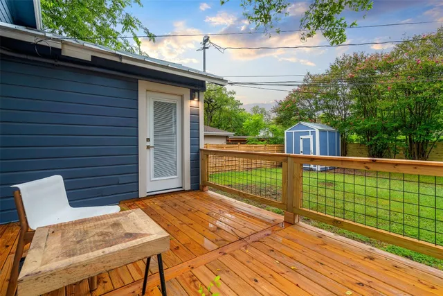 a view of a deck with wooden floor and fence next to a yard