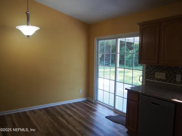a view of a kitchen with wooden floor and a window